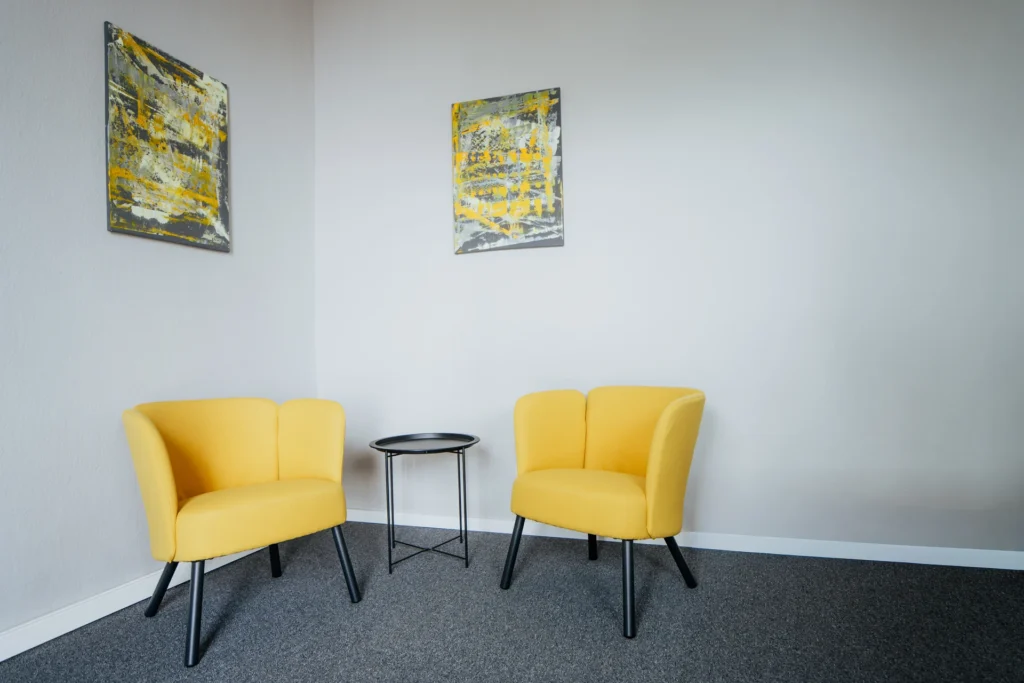 Gemütliche gelbe Sessel mit Beistelltisch in modernem Raum, ideal für entspannte Gespräche und Meetings.