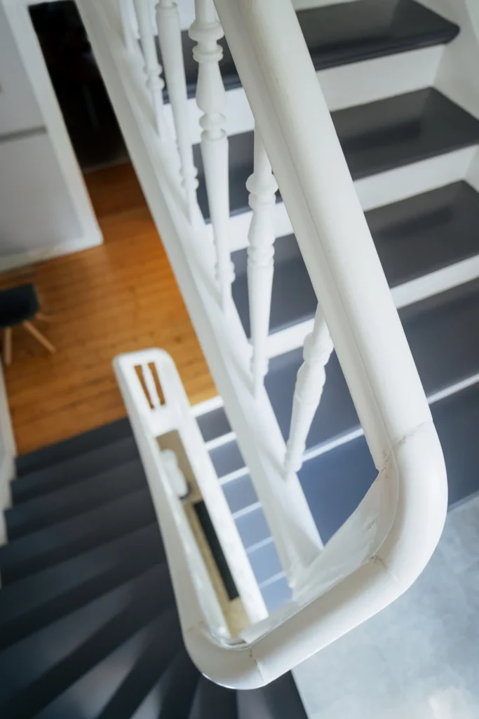 Treppenhaus mit weißen Geländern und dunklen Stufen in einem modernen Wohnraum.
